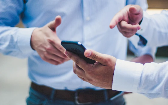 One person points to the screen of a smartphone